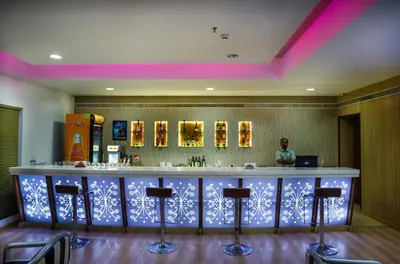 a bar in a restaurant with a woman standing behind it at Hotel Elite Palazzo in Kāladi