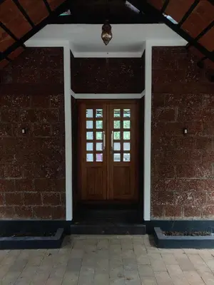 a wooden door in a brick building with a brick wall at ExoticaHolidays in Sultan Bathery