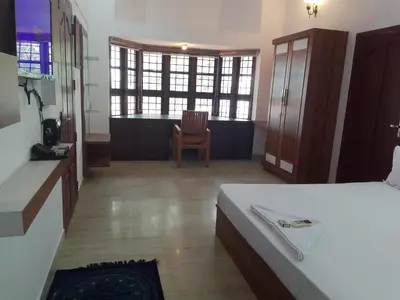 a bedroom with a bed and a desk and a chair at Liberty House - SeaView in Kozhikode