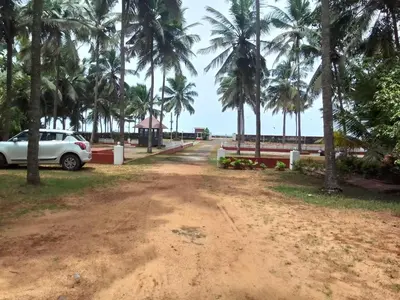 a dirt road with palm trees and a white car at Liberty House - SeaView in Kozhikode