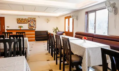 a dining room with two tables and chairs at Treebo Premium Akshaya Mahal Inn in Mysore