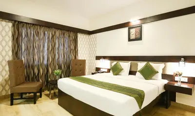 a hotel room with a bed and a chair at Treebo Premium Akshaya Mahal Inn in Mysore