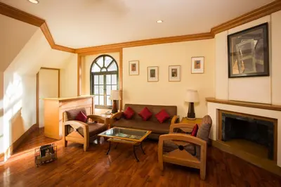 a living room with a couch and a fireplace at Fortune Resort Sullivan Court, Ooty - Member ITC Hotels' Group in Ooty
