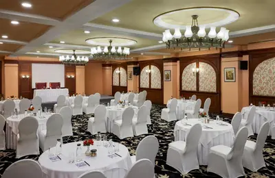 a conference room with white tables and chairs and chandeliers at Fortune Resort Sullivan Court, Ooty - Member ITC Hotels' Group in Ooty