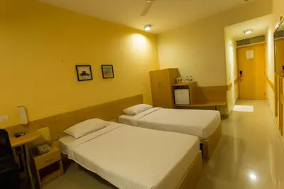 a hotel room with two beds and a television at Ginger Mysore in Mysore