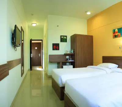 a hotel room with two beds and a tv at Ginger Mysore in Mysore