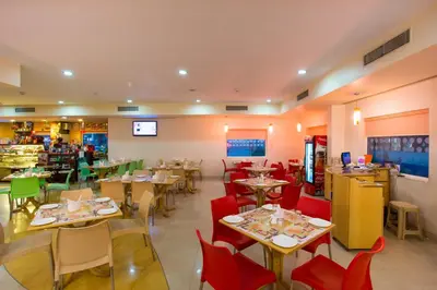 a restaurant with tables and chairs in a room at Ginger Mysore in Mysore