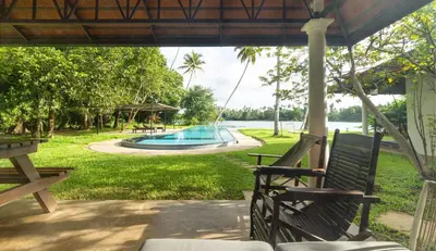 a porch with two benches and a swimming pool at Cranganor History Café & Riverside Château in Parūr