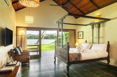 a bedroom with a canopy bed with a view of the water at Cranganor History Café & Riverside Château in Parūr