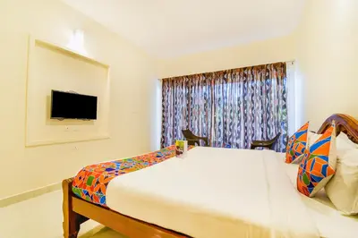 a bedroom with a large bed and a television at FabHotel Vinu Valley Resorts - Nr Ketti Valley View Point in Ooty