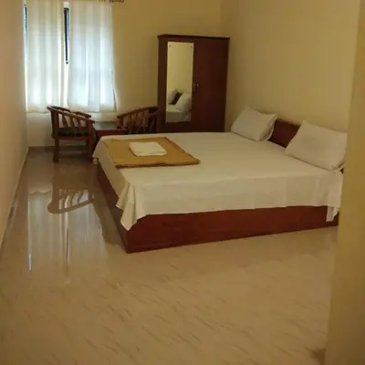 a bedroom with a bed and a table and a mirror at Manjira Lodge in Guruvāyūr