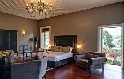 a bedroom with a bed and chairs and a chandelier at Talayar Valley Bungalow in Idukki