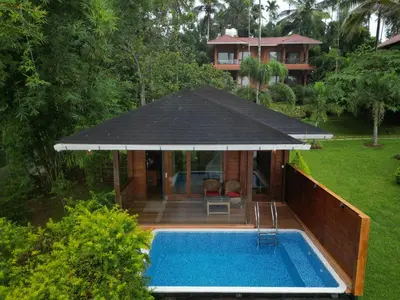 a house with a swimming pool and an umbrella at LakeRose Wayanad Resort in Ambalavayal