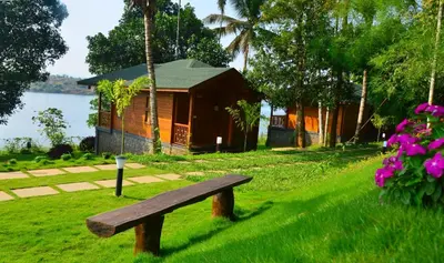 a wooden bench sitting in the grass in front of a house at LakeRose Wayanad Resort in Ambalavayal