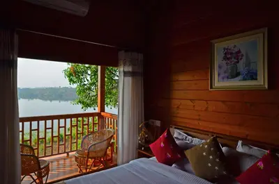 a bedroom with a bed and a balcony with a view at LakeRose Wayanad Resort in Ambalavayal