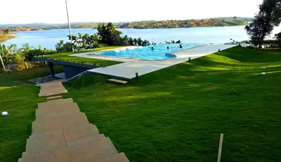 a large swimming pool next to a body of water at LakeRose Wayanad Resort in Ambalavayal