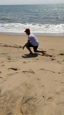 a young boy is playing in the sand on the beach at Takashi Homestay North Paravur Near Muziris in North Paravur