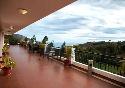 a balcony with tables and chairs and a view of the ocean at Mount n Mist in Ooty