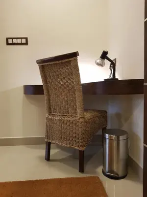 a wicker chair sitting at a desk with a lamp at Riyavar Luxury Stay in Siddapur