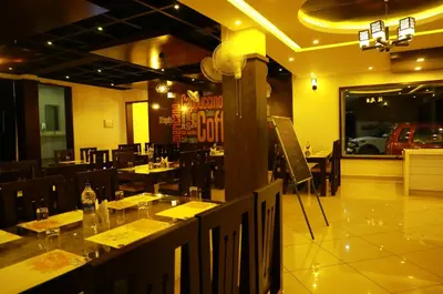 a dining room with tables and chairs in a restaurant at Wayanad Royal Crown in Kalpetta