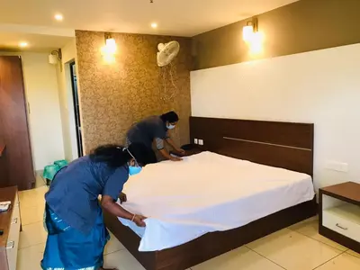 two people are making a bed in a room at Wayanad Royal Crown in Kalpetta