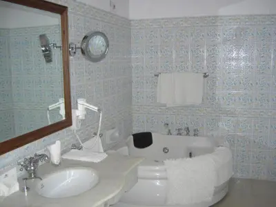 a bathroom with a sink and a bath tub at WelcomHeritage Fernhills Royal Palace in Ooty