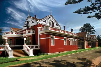 a large red house with white trim on a street at WelcomHeritage Fernhills Royal Palace in Ooty