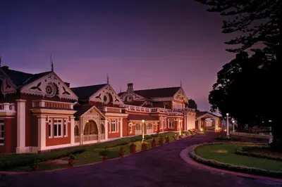 a large house with a driveway at night at WelcomHeritage Fernhills Royal Palace in Ooty