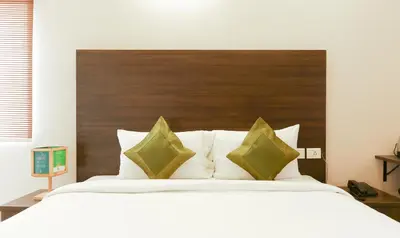a bedroom with a large white bed with a wooden headboard at Treebo Hi Line Apartments Kalapatti in Coimbatore