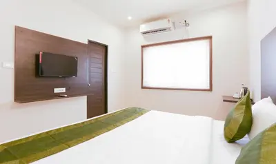 a bedroom with a bed with a tv on the wall at Treebo Hi Line Apartments Kalapatti in Coimbatore