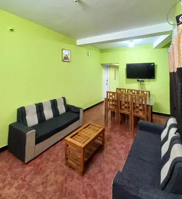 a living room with a couch and a table and a tv at smile stone individual cottage in Ooty