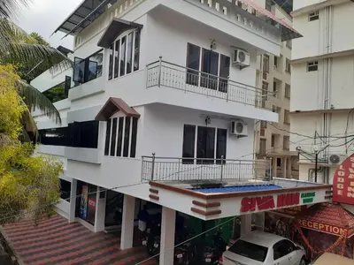 a white building with a balcony on a street at Siva Inn in Guruvāyūr