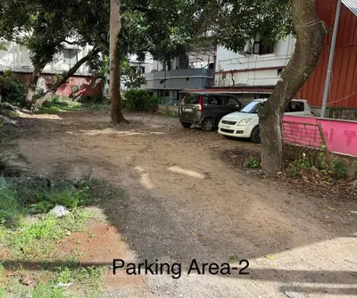 a parking area with two cars parked next to a building at Siva Inn in Guruvāyūr