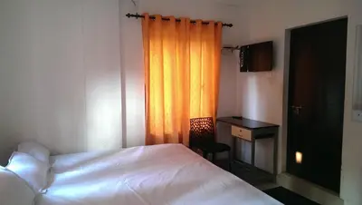 a bedroom with a bed and a desk and a curtain at Siva Inn in Guruvāyūr