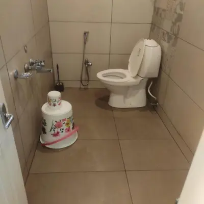 a bathroom with a toilet and a cake on the floor at Snowdrops Ooty in Ooty