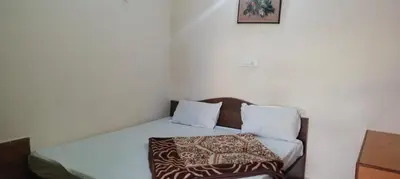 a bedroom with a bed with a blanket on it at Hill Inn Rooms an HomeStay in Ooty