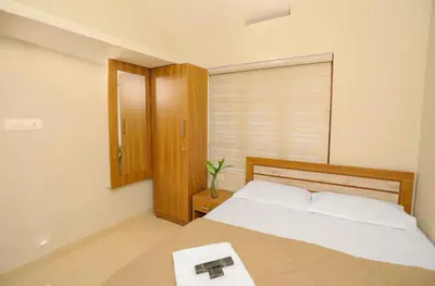 a bedroom with a large bed and a wooden cabinet at Nandanam Villa in Kaniyāmbetta