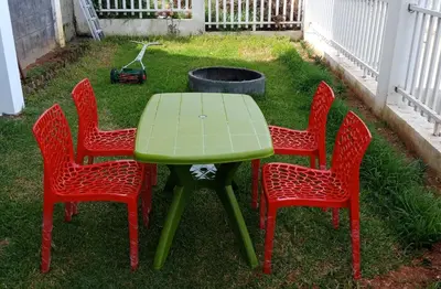 four red chairs and a green table in a yard at Aanvis inn in Ooty