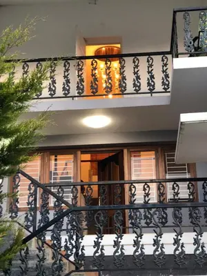 a balcony of a house with a black railing at Aanvis inn in Ooty