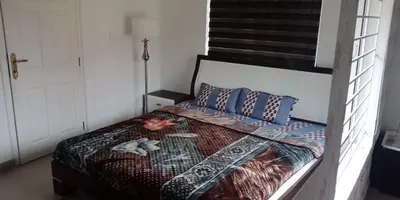a bedroom with a bed with a comforter and pillows at Aanvis inn in Ooty
