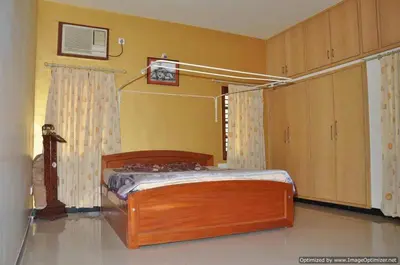 a bedroom with a wooden bed in a room at Suvarna Luxury Home Stay in Mysore