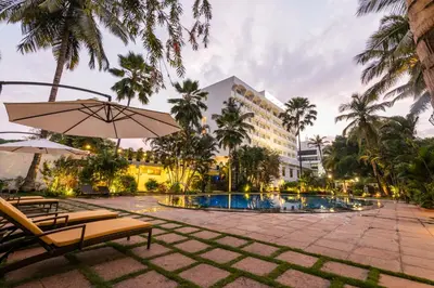 a resort pool with two chairs and an umbrella at Southern Star,Mysore in Mysore