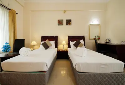 a hotel room with two beds and a mirror at Rose International Hotel in Nilambūr