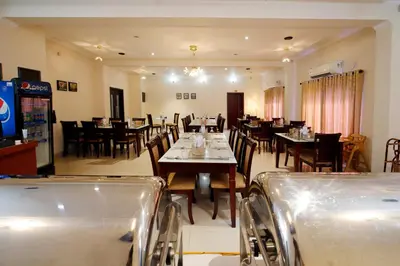a dining room with tables and chairs in a restaurant at Rose International Hotel in Nilambūr