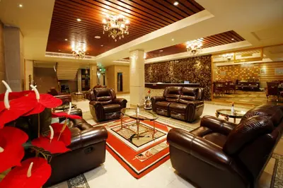 a lobby with leather furniture and red flowers at Hotel Park Residency in Nilambūr