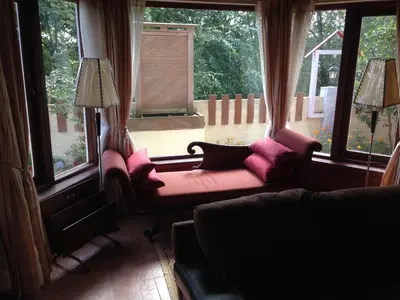 a living room with two chairs and two windows at Colonial 4 B/R Home, Great for Families, Coonoor in Coonoor