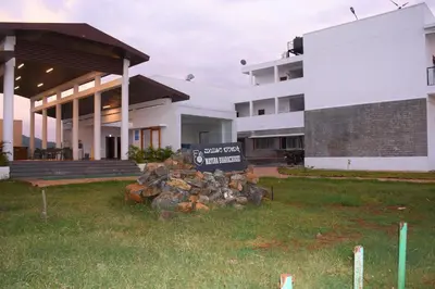 a sign sitting in the grass in front of a building at KSTDC Hotel Mayura Bharachukki, Shivanasamudra in Sivasamudram