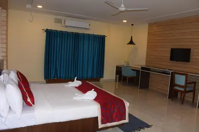 a bedroom with a bed and a desk and a television at KSTDC Hotel Mayura Bharachukki, Shivanasamudra in Sivasamudram