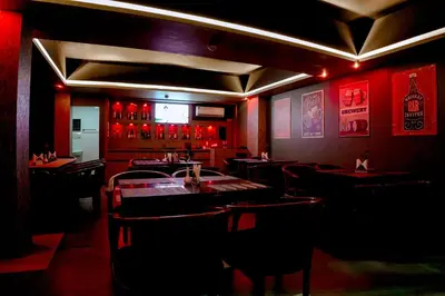 a restaurant with a bar with tables and chairs at Queens Hotel in Kozhikode