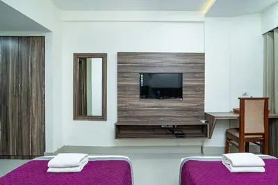 a room with two beds and a flat screen tv at Nexstay Crystal Residency in Kozhikode